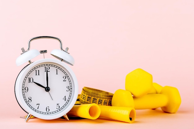 Time for a workout clock and dumbbells with a colorful pink background