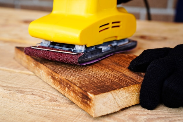 Timmerman arbeider werken met hout schuren en verwijderen van de toplaag met een schuurmachine oppervlak polijsten...