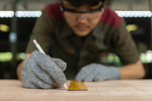 Timmerman die aan houtbewerkingsmachines werken in timmerwerkwinkel. Deskundige timmerman die een stuk hout in zijn houtbewerkingsworkshop snijdt.