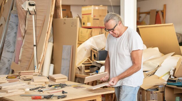 Timmerman die aan houten vaartuigen werkt in de werkplaats die houten meubelbanner produceert