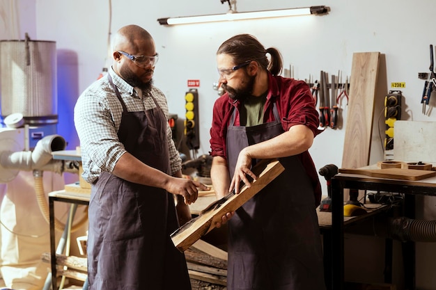 Timmerman die houtblokken vasthoudt brainstormt met een collega die hout verwerkt