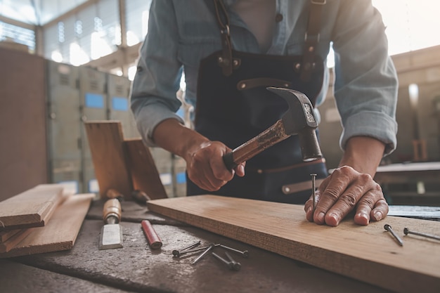 Timmerman die met apparatuur aan houten lijst in timmerwerkwinkel werken.