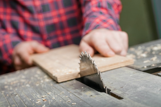 Timmerman die met lijstzaag werkt in workshop. Detailopname.