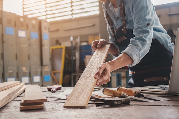 Timmerman die met materiaal aan houten lijst in timmerwerkwinkel werken.