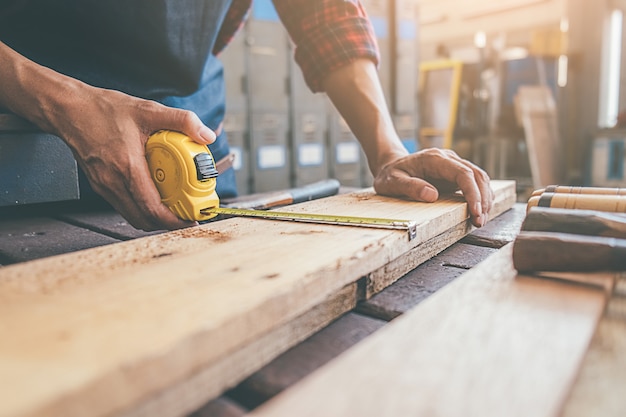 Timmerman die met materiaal aan houten lijst in timmerwerkwinkel werken.