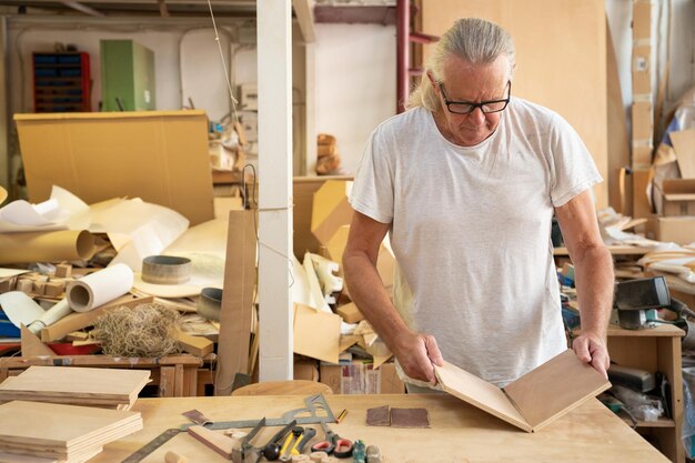 Foto timmerman-kunstenaar die werkzaamheden met hout verricht op een werkplek voor de productie van houten meubels