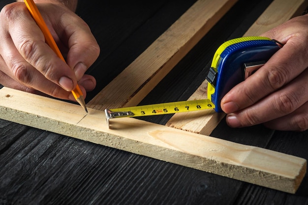 Timmerman maakt potloodstrepen op een blok hout Handen van de meester-closeup op het werk