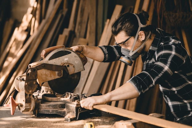 Timmerman man met behulp van elektrische houtsnijder machine met veiligheidsuitrusting bescherming in hout werkplaats