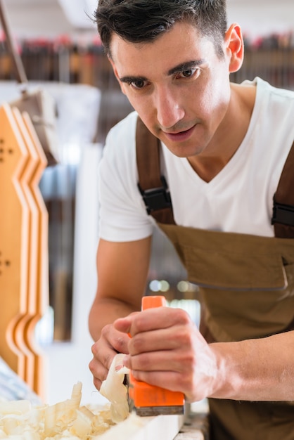 Timmerman met houten planer die aan stuk werkt