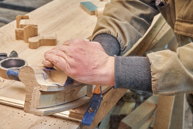 Timmerman schuurt buigen houten reling met schuurpapier in werkplaats close-up