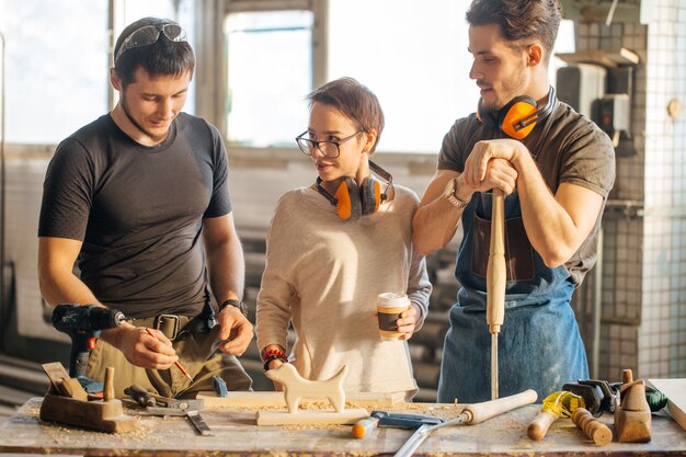 Timmerman training female apprentice to plane gebruiken