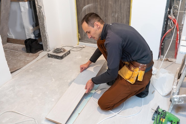 Timmerman werknemer laminaatvloer in de kamer installeren.