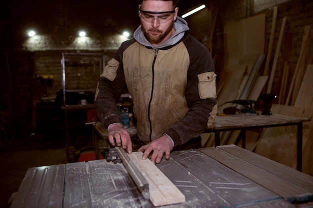 Timmerman zaagt een houten plank op een cirkelvormige machine Productiefoto
