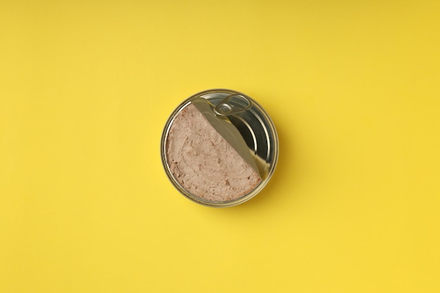 Tin can of pate on yellow background