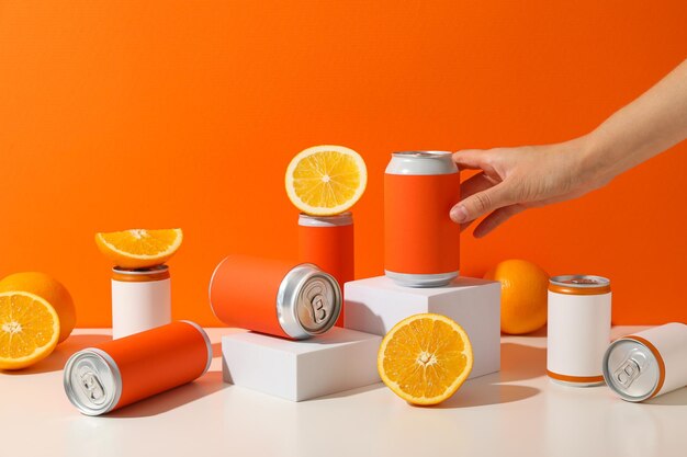 Tin cans oranges and hand on orange background