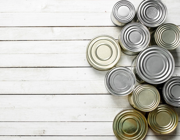 Tin cans with food on white wooden table