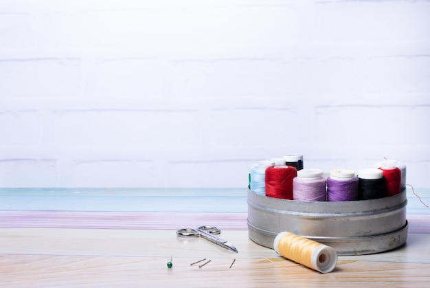 Tin with spools of threads of various colors and other sewing items