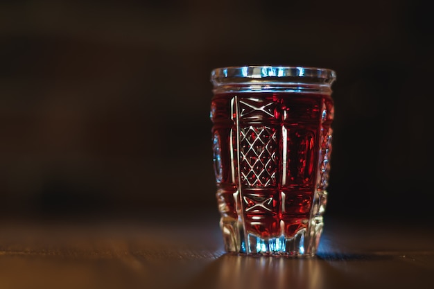 Foto tintura di colore rosso in un bicchiere di cristallo si erge su un tavolo di legno