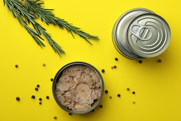 Photo tins with canned tuna on yellow background