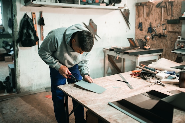 Photo tinsmith blacksmith use hammer working in his workshop. blacksmiths workshop. young tinsmith in his workshop.