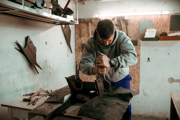 Tinsmith-smid gebruikt hamer in zijn werkplaats.