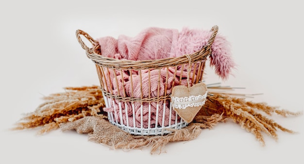 Photo tiny basket decor for newborn studio photoshoot filled with knitted blanket and toy heart closeup. infant baby handmade furniture