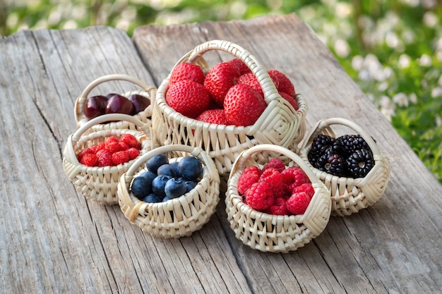 Tiny baskets of berries on old wooden board