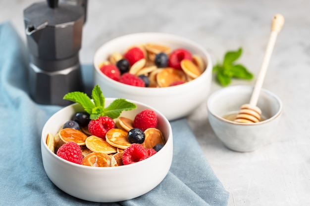 Tiny cereal small pancakes with blueberries, raspberries, mint and honey for a breakfast