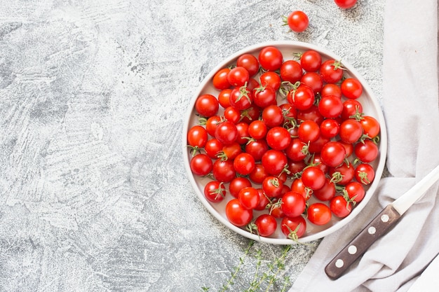 Piccoli pomodorini (ciliegini, pachino, cocktail). gruppo di pomodori ciliegia su un cemento grigio maturo e succosi pomodori ciliegia