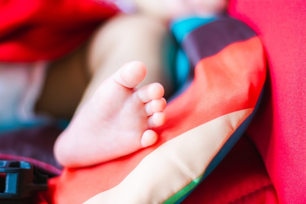 Tiny feet of cute Asian baby sleeping on car seat