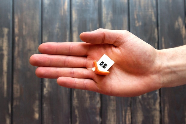 A tiny figurine a toy a model of a house is lying on an open male hand