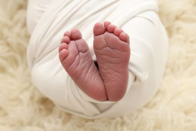 生まれたばかりの赤ちゃんの小さな足 白い毛布に包まれた新生児の柔らかい足 新生児のつま先かかとと足のクローズアップ マクロ写真