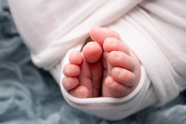 The tiny foot of a newborn Soft feet of a newborn in a white blanket and on a blue background Close up of toes heels and feet of a newborn baby Studio Macro photography Woman39s happiness