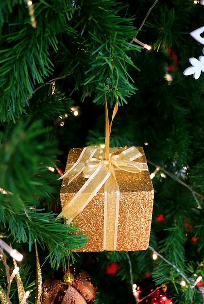 Foto confezione regalo glitter oro minuscolo con fiocco in nastro d'oro ornamento natalizio appeso all'albero di natale