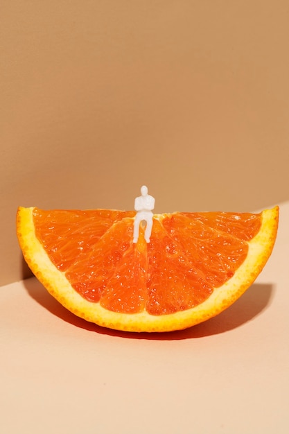 Tiny man sitting on an orange wedge