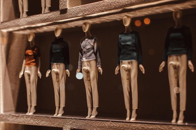 Tiny mannequins dressed in beige trousers and knitted sweaters  Autumn winter fashion collection