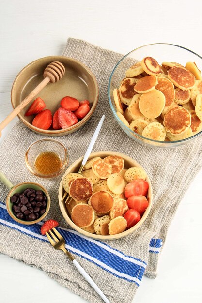 Tiny Pancake Cereal with Strawberries and Mint Leaves on a White Background. Trendy food in 2020 with Copy Space.