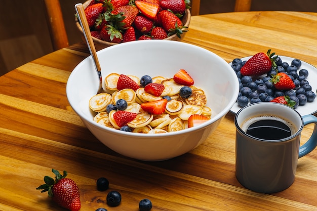 Tiny pancakes for breakfast. Pancakes with strawberries and blueberries cooked in the morning for breakfast in the home kitchen. 