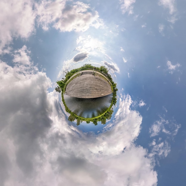 Tiny planet in blue overcast sky with beautiful clouds with
transformation of spherical panorama 360 degrees spherical abstract
aerial view curvature of space