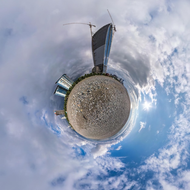 Tiny planet in blue sky with clouds in city center near modern
skyscrapers or office buildings transformation of spherical 360
panorama in abstract aerial view