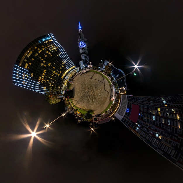 Tiny planet in night sky in city center near modern skyscrapers\
or office buildings transformation of spherical 360 panorama in\
abstract aerial view