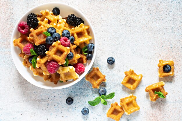 Tiny waffles with berries in a white bowl