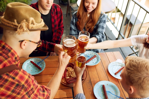 Tio view image of young people friends cheerfully spending time together at cafe pub clinking