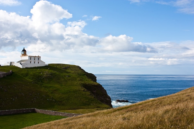 Tipical panorama of Scotland, with a lighthouse and blue sky