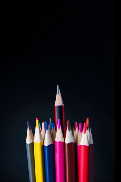 The tips of colored pencils and in the center of a simple pencil on black