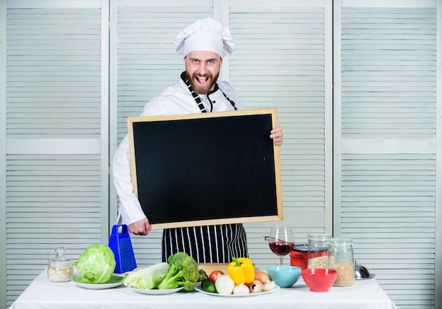 Tips om te koken als een pro Bekijk kooktips Man koksmuts schort houd schoolbord kopieerruimte Receptconcept Stap voor stap heerlijke maaltijd koken Menu voor vandaag Lijst ingrediënten voor het koken van gerecht