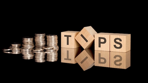 Tips text on wooden cubes on dark backround with coins business concept