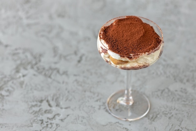 Tiramisu dessert in a glass on gray surface