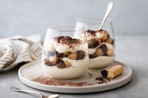 Tiramisu dessert in a glass on a light background