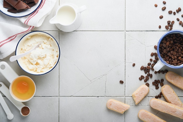 Tiramisu dessert Ingrediënten voor het maken van dessert tiramisu Italiaans eten dessert Tiramisu koken met alle benodigde ingrediënten cacao koffie mascarpone kaas op grijze stenen achtergrond Kopieer ruimte